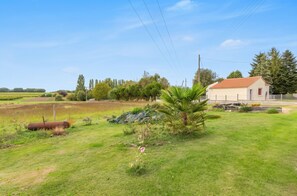 Un paysage rural avec une maison, des champs ouverts et un ciel dégagé.