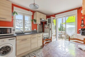 A compact kitchen with a washing machine, microwave, and a dining area with a table.
