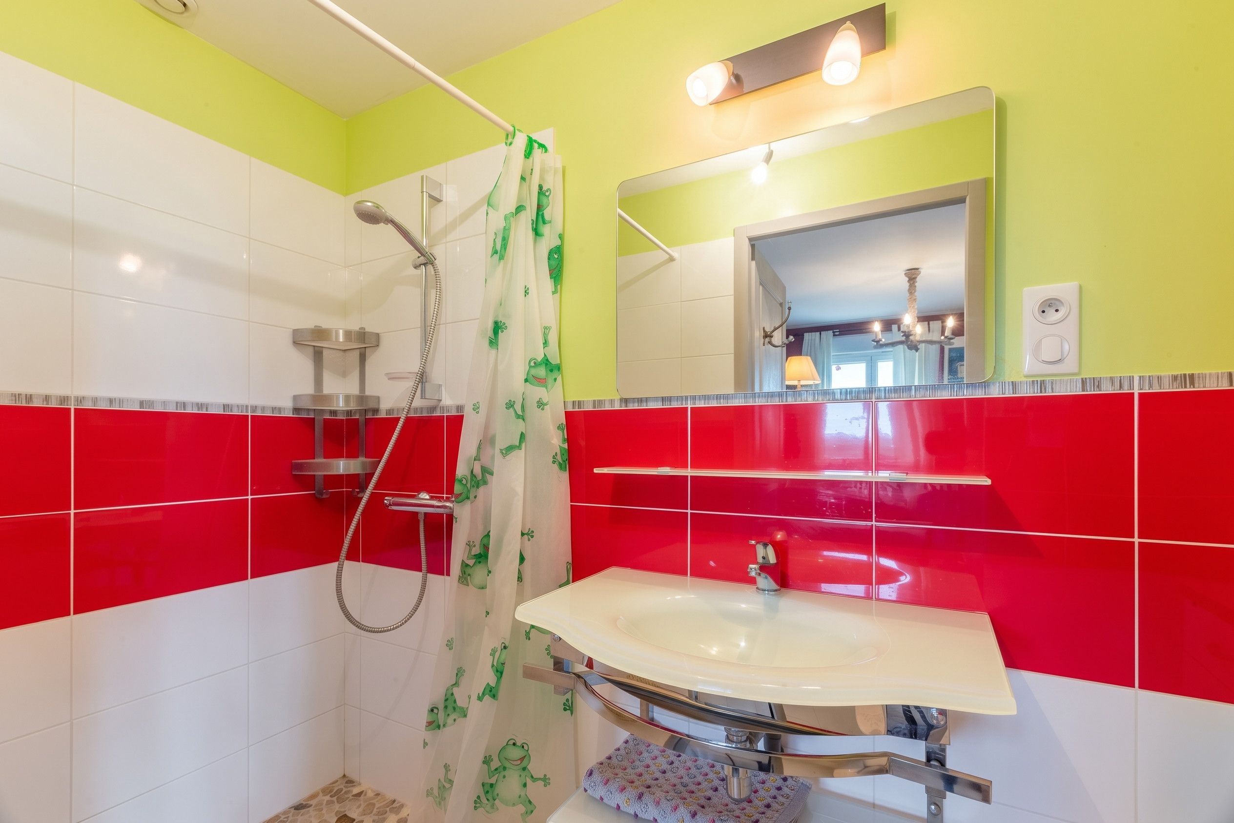 Een badkamer met een douche, wastafel en spiegel.