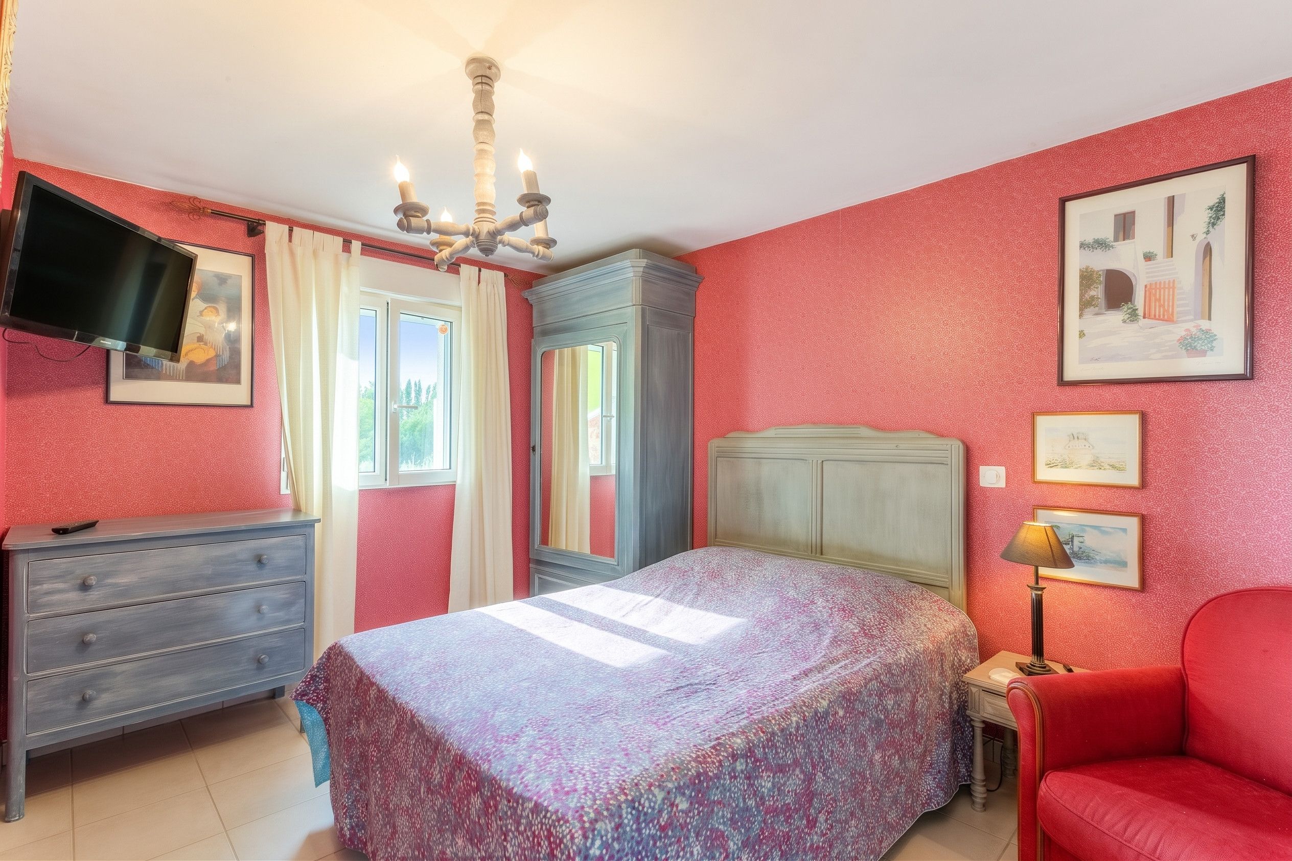 Une chambre à coucher comprenant un lit, une commode, une coiffeuse et un téléviseur.