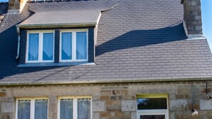 A stone house with a tiled roof, a front door, and a small garden with a table and chairs. - Homerez - House in Sourdeval (Sourdeval)