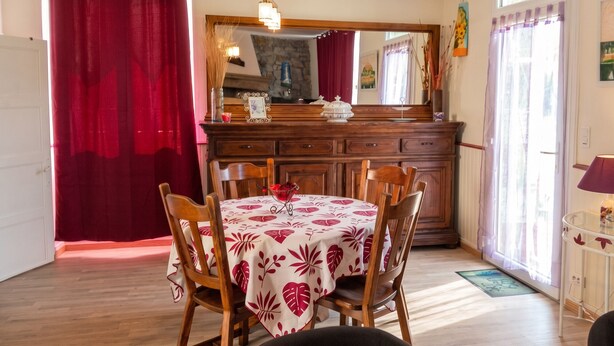 A dining area with a table set for four, wooden chairs, a mirror above the table, and a window with curtains. - Homerez - House in Sourdeval (Sourdeval)