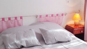 A bed with a quilted white cover, a pink headboard, and a painting of a building on the wall. - Homerez - House in Sourdeval (Sourdeval)