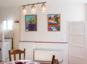 A dining area with a table, chairs, and two paintings on the wall.
