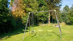 A swing set in a grassy area with trees in the background. - Homerez - House in Sourdeval (Sourdeval)