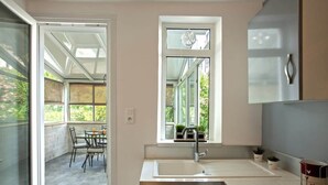 Eine moderne Küche mit großem Fenster, einer Spüle und einem Essbereich mit Stühlen.