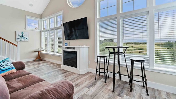 A spacious living room with a large TV, a fireplace, and a view of the outdoors. - Pets OK, Amazing View, Steps to Town & Beach (Seas) (Long Beach)