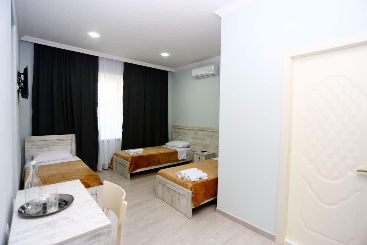 Habitación de hotel con dos camas, una mesa con bandeja, una silla y un equipo de aire acondicionado.