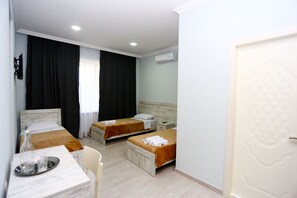 Een hotelkamer met twee bedden, een tafel met dienblad, een stoel en een airconditioner.