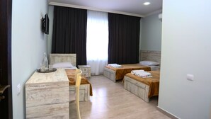 Hotelkamer met twee bedden, een bureau met stoel, een aan de muur bevestigde televisie en een raam met gordijnen.