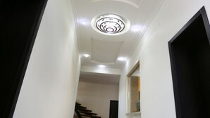 Een hal met een plafondlamp, een trap en een deur aan de rechterkant.