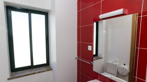 A bathroom with a window, a sink, a toilet, and a mirror. - Faro Albacor Residence - Hostel (Faro)