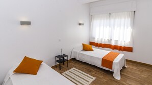 A room with two beds, a small table, and a window with curtains. - Faro Albacor Residence - Hostel (Faro)