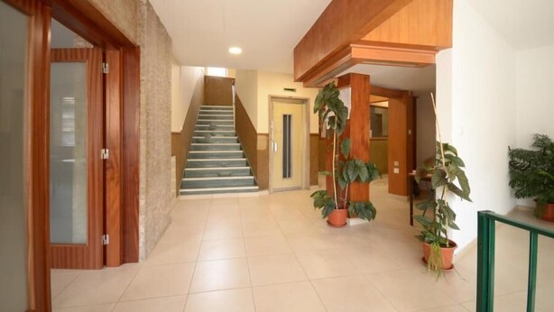 A spacious hallway with a staircase leading to another floor, wooden doors, and potted plants. - Faro Albacor Residence - Hostel (Faro)