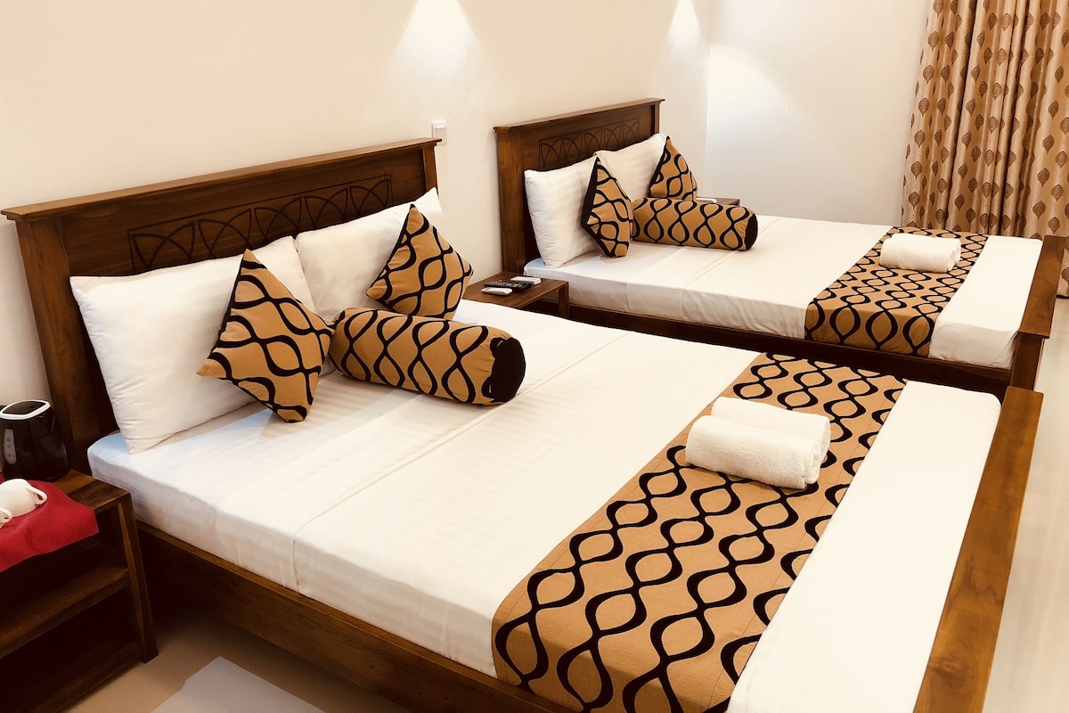 Duas camas de solteiro com cabeceiras de madeira, roupa de cama branca e almofadas estampadas.