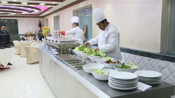 Un buffet avec plusieurs présentoirs de nourriture et du personnel pour servir les clients.