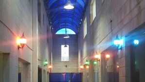 Un couloir avec un plafond aux nuances bleues, un sol carrelé et de nombreuses portes de part et d’autre.