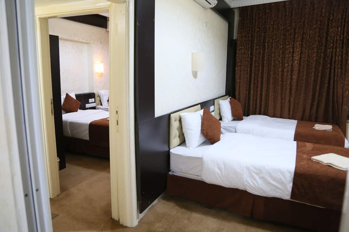 A hotel room with two beds, a large mirror, and a curtain.
