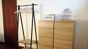 Ein Zimmer mit einem Holzschrank, einem Holzstuhl und einem Kleiderständer aus Metall.