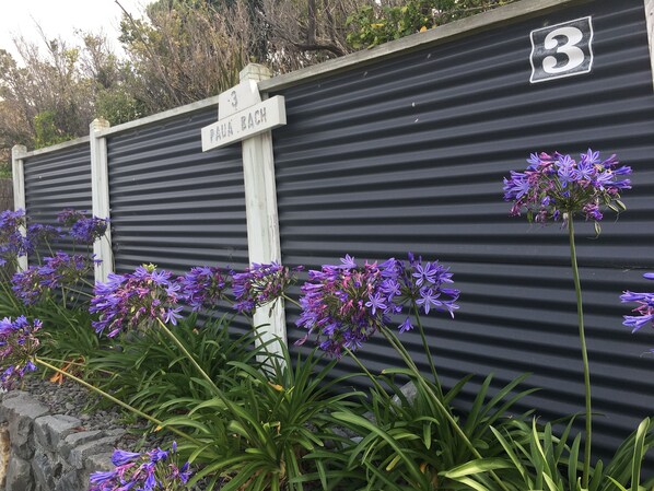 A black corrugated metal wall with a white sign reading "3 PAUÄ. BACH" and a number "3" above it.