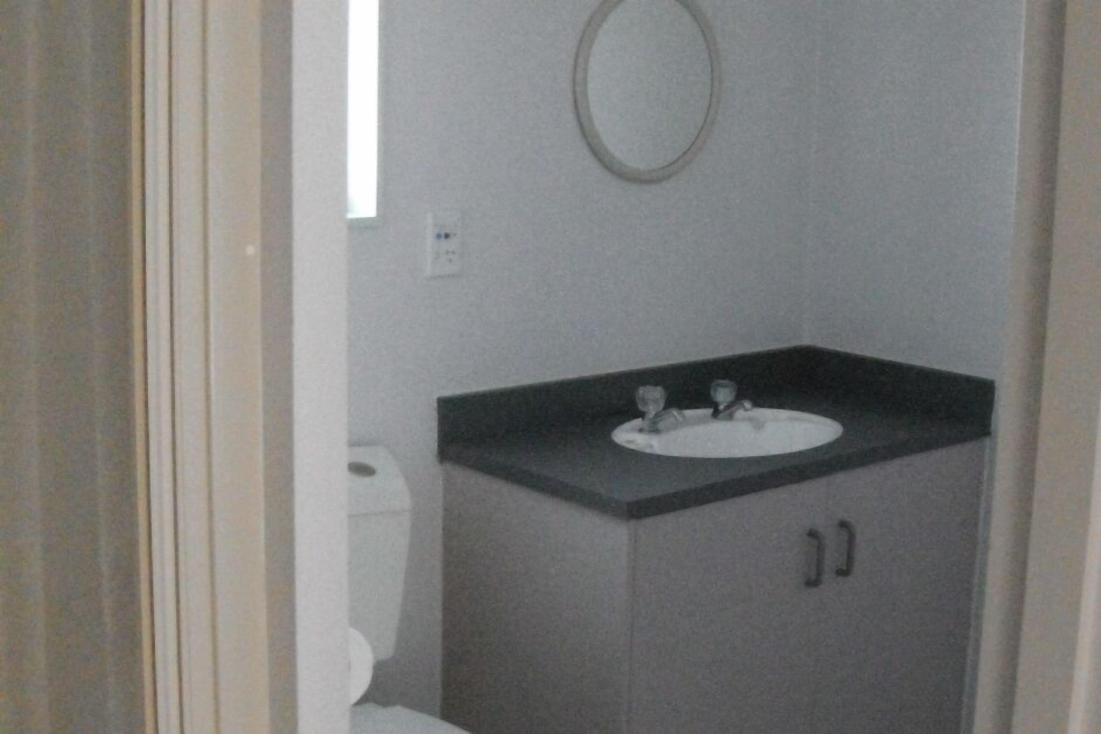 Un bany petit amb un vàter, un lavabo blanc i un mirall.