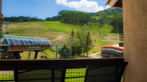 A view from a balcony overlooking a green field with a ski lift and a building labeled "Silver Queen". - Ski-in/Ski-out, 1 bedroom at the heart of the Resort Base Area! (Mt. Crested Butte)