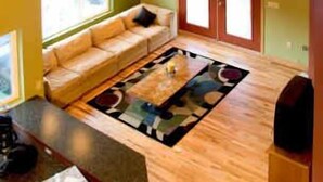 A spacious living room with a large sofa, a coffee table, and a wooden floor. There is a window providing natural light and a door leading to another room. - Large group(walking distance to Alyeska Resort) (girdwood)