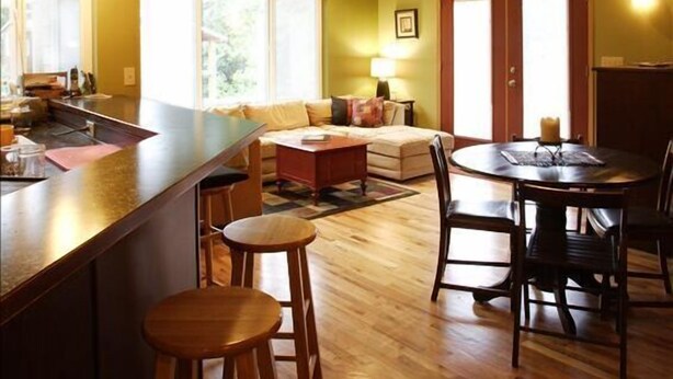 A modern kitchen with a bar area, wooden flooring, and a dining table with chairs. - Large group(walking distance to Alyeska Resort) (girdwood)