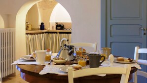Mesa de café da manhã posta com diversos pratos, chaleira e cafeteira.
