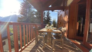 A wooden deck with a table set for two, overlooking a mountainous landscape. - Luxury detached 12-person chalet, few steps from the slopes in heart Alpe d'Huez (Oz)