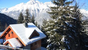 A wooden cabin with a sloped roof covered in snow, surrounded by snow-covered trees and mountains in the background. - Luxury detached 12-person chalet, few steps from the slopes in heart Alpe d'Huez (Oz)