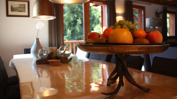 A dining table with a fruit bowl containing oranges, apples, and grapes. - Luxury detached 12-person chalet, few steps from the slopes in heart Alpe d'Huez (Oz)