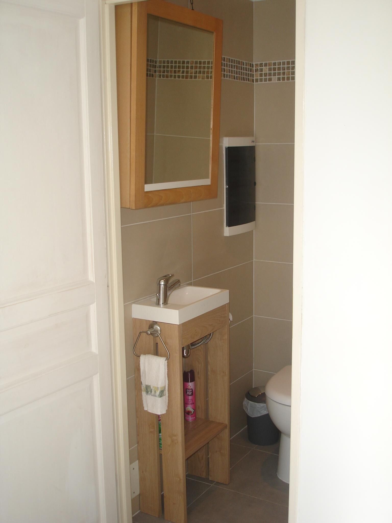 A bathroom with a wooden vanity, a white sink, a mirror, and a toilet.