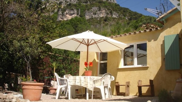 Eine Terrasse mit Tisch, Stühlen und einem Blumentopf, mit Blick auf die Berge.