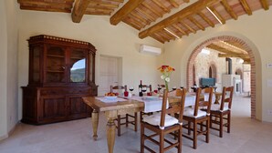 Un espace repas comprenant une table et des chaises en bois, un buffet et un mur en briques en forme d’arc.