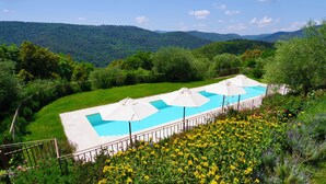 A swimming pool with white umbrellas, surrounded by lush greenery and hills in the background. - Mulino della Solaia, Arceno Rentals Club, Luxury Villa in Tuscany, pool, wifi (Monticiano)
