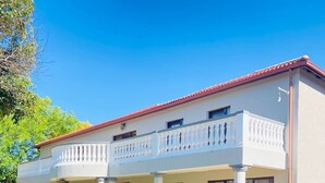 A two-story building with a red-tiled roof, white exterior walls, and a balcony with white balustrades. - Airport Royal Guest House (Kempton Park)