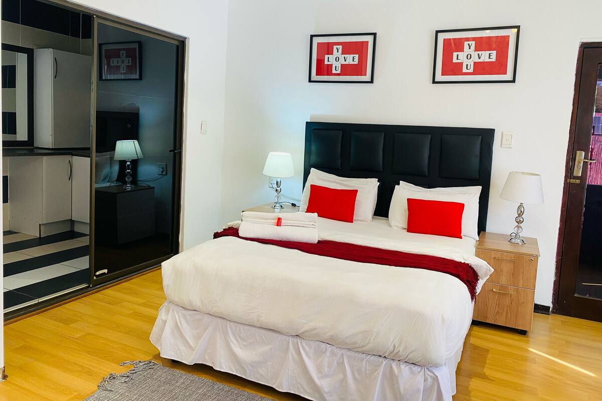 Une chambre d’hôtel avec un lit, une table de chevet, une lampe, une armoire et deux tableaux encadrés au mur.
