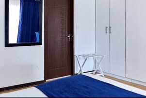 Un dormitorio con puerta de madera, armario blanco y una pequeña mesa blanca.