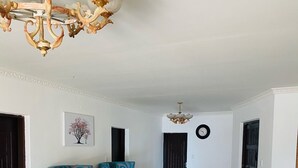 A spacious hallway with a chandelier, two blue patterned armchairs, a rug, and a wall clock. - Airport Royal Guest House (Kempton Park)