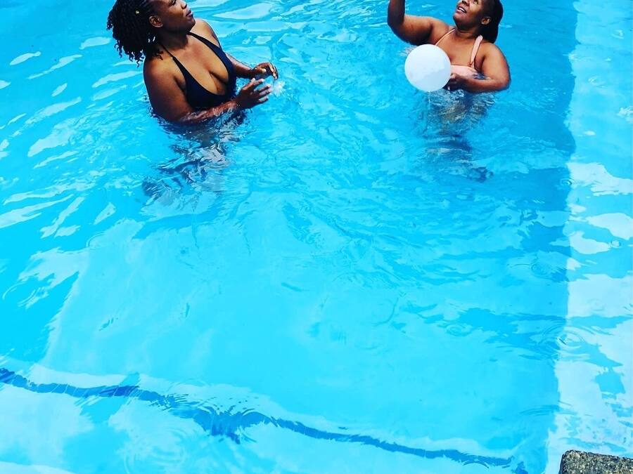 Ein Schwimmbecken mit zwei Personen, die mit Luftballons spielen.
