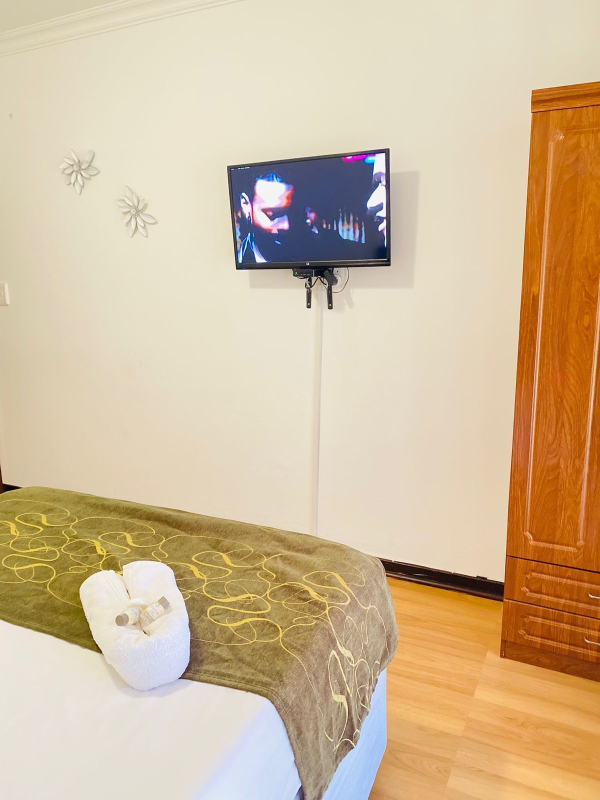 Ein Hotelzimmer mit Bett, Wandfernseher und Holzschrank.