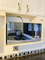 Una cocina con microondas integrado, cafetera y un reloj digital en la pared.