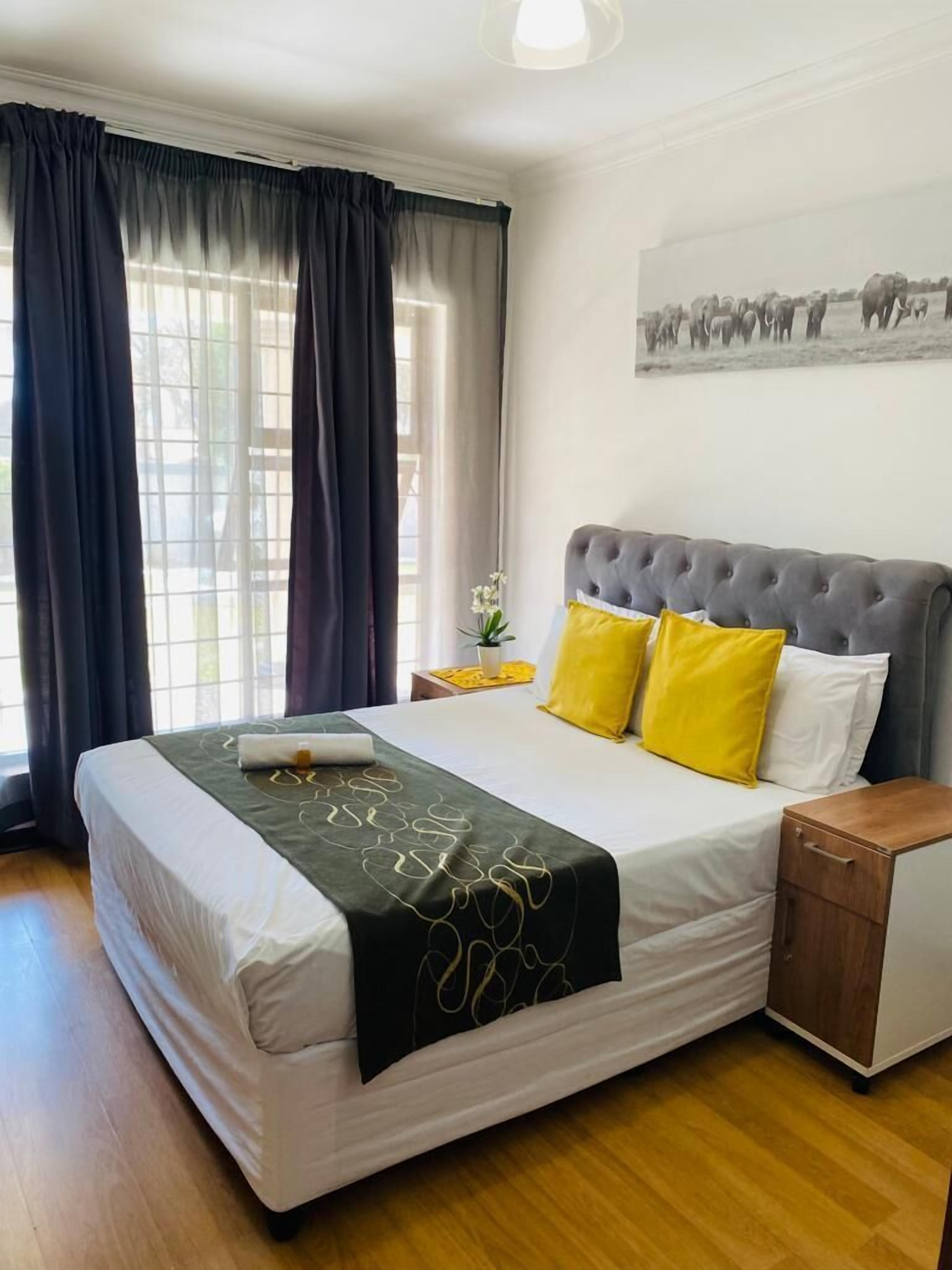 Une chambre bien rangée, avec un grand lit, une table de chevet et une petite table d’appoint.