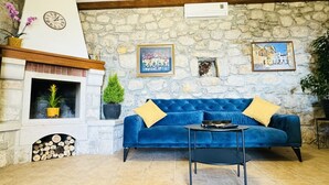 Ein gemütliches Wohnzimmer mit Steinwand, Kamin, einem blauen Sofa und einem kleinen Tisch.