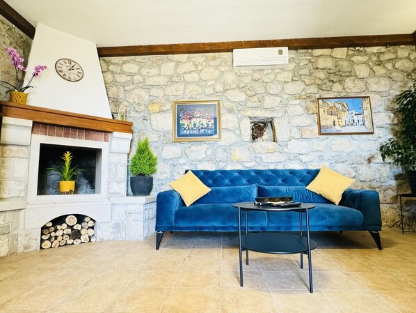 A cozy living room with a stone wall, a fireplace, a blue sofa, and a small table.