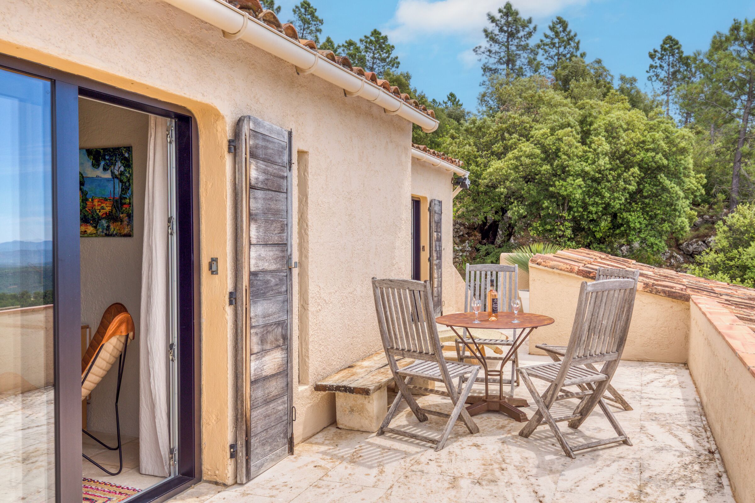 Un patio con mesa y sillas, una puerta y vistas a árboles.