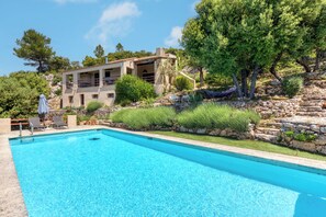 A clear blue pool with a stone border, surrounded by greenery and a stone staircase. - 9 Guest Villa with Heated Pool, Spa, Pétanque & Panoramic View (Tourtour)