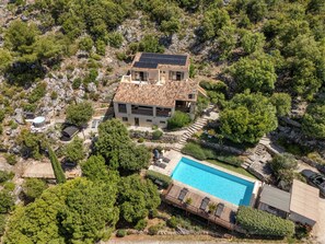 A large house with a swimming pool, surrounded by trees and rocky terrain. - 9 Guest Villa with Heated Pool, Spa, Pétanque & Panoramic View (Tourtour)