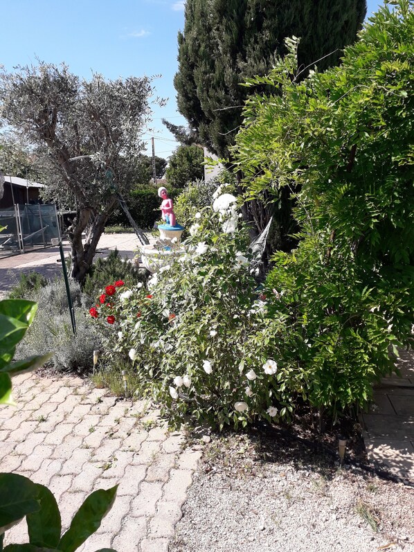 Un jardín con diversas plantas, una hamaca y una estatua.